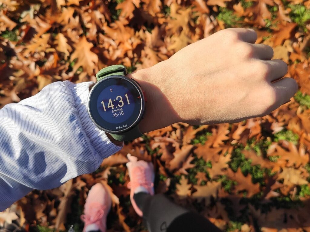 Die neue Polar Vantage V2 vor herbstlichen Laubblättern.